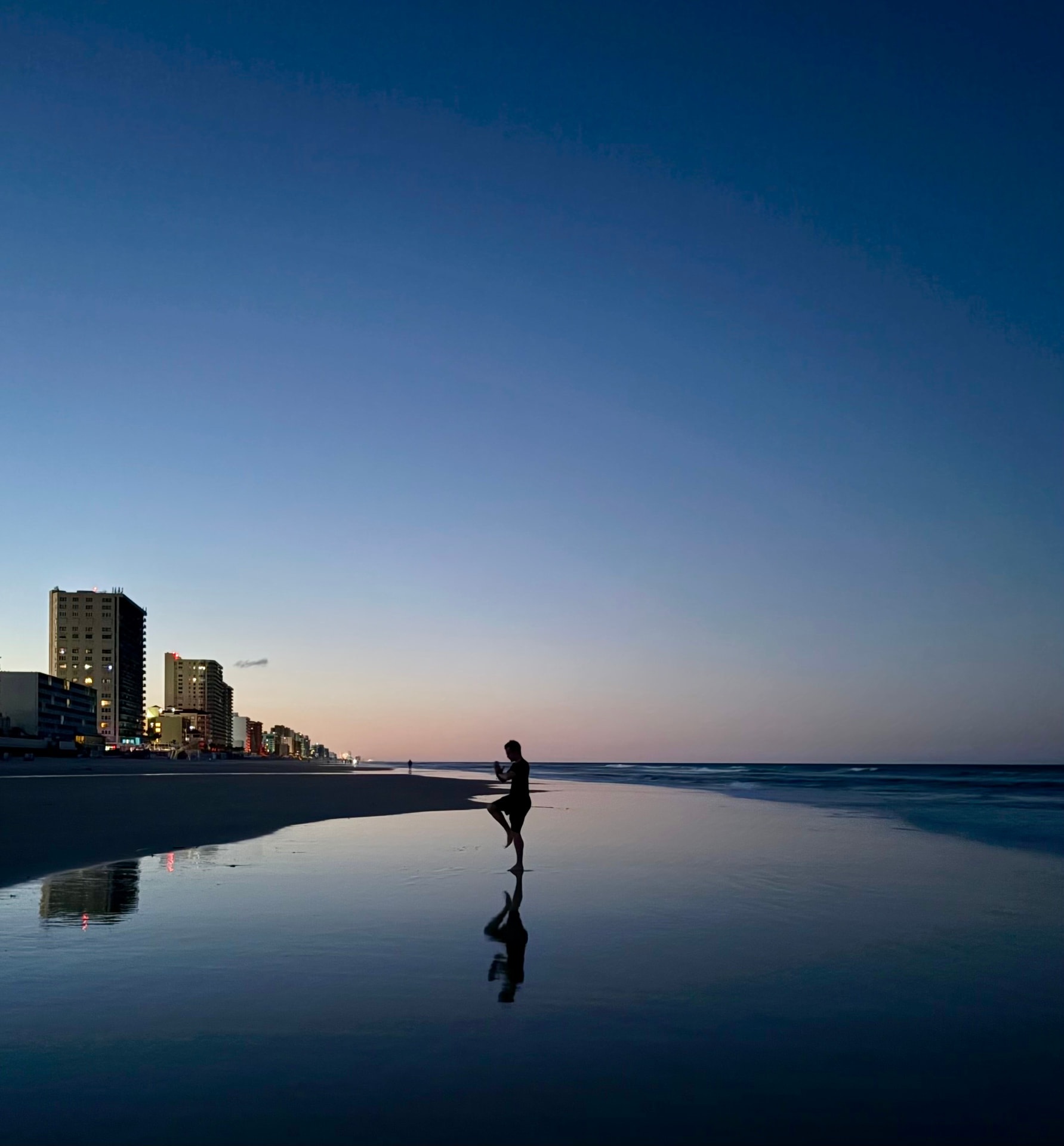 Joseph Eldredge in silhouette on the shoreline at dusk